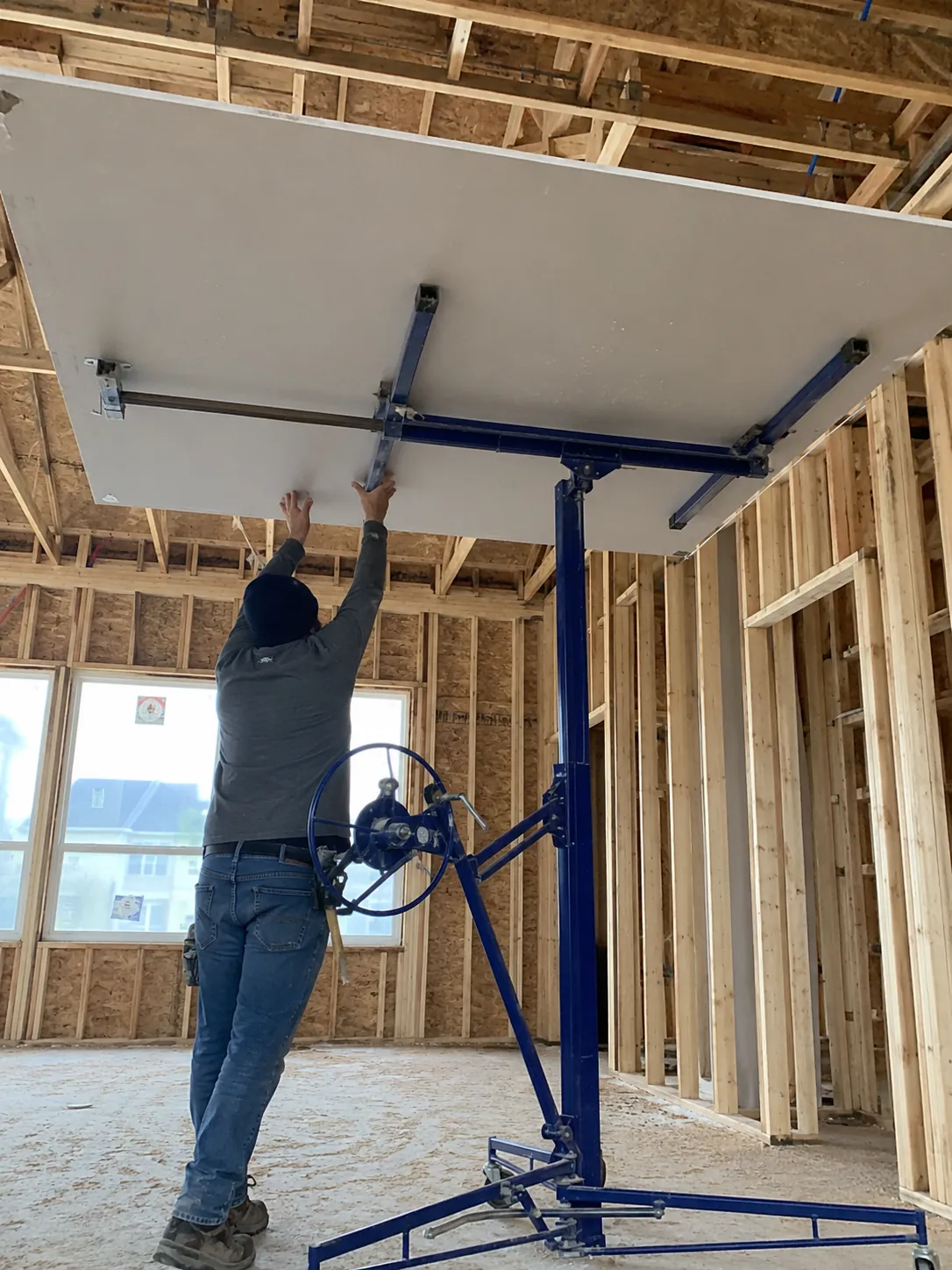 Panel lift raising a drywall sheet to a high ceiling on a new build