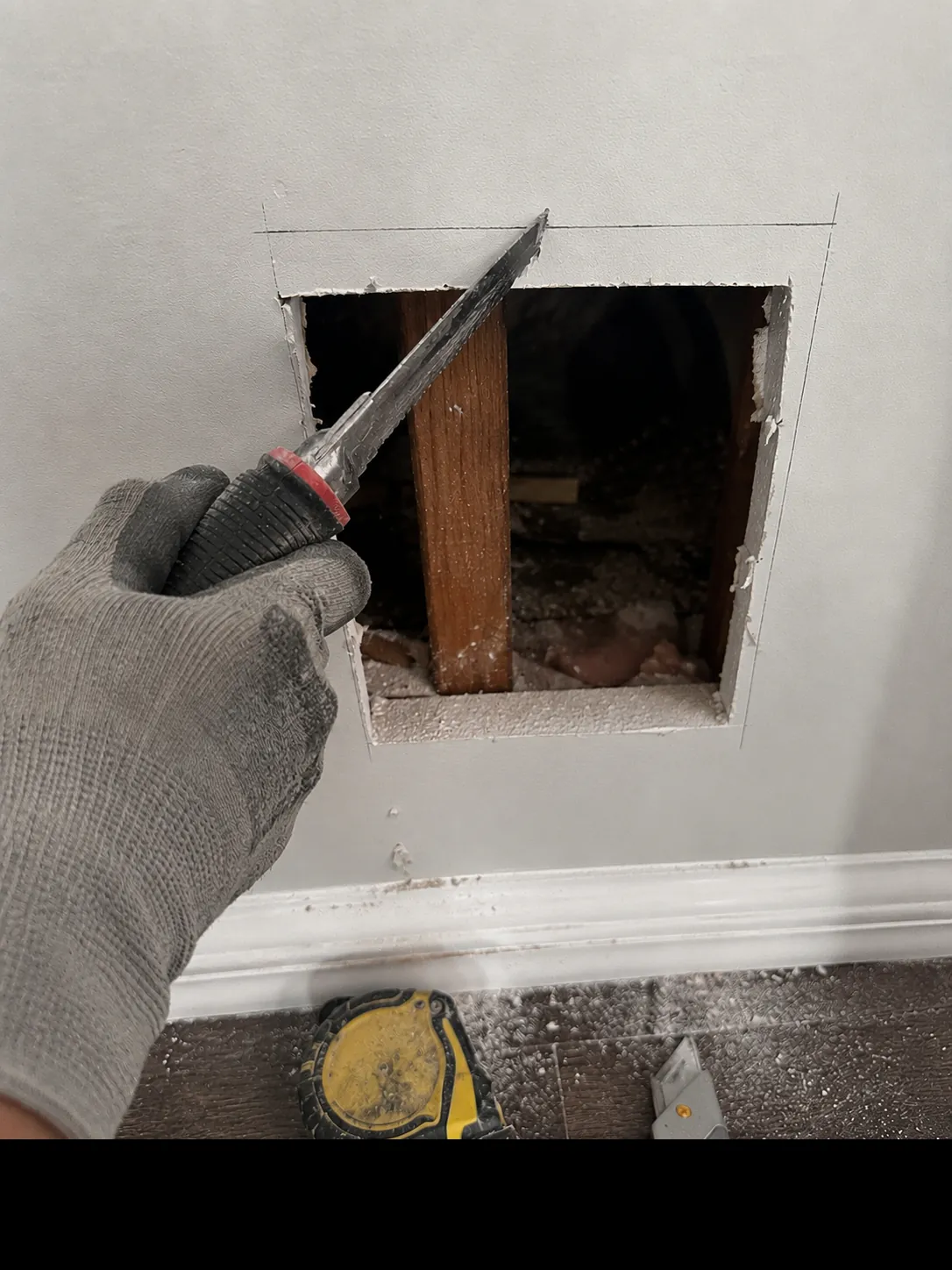 Cutting out a damaged section of drywall for a patch repair